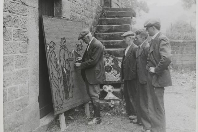 One of the well-dressers demonstrating to other villagers during the Dressing The Well At Youlgreave.