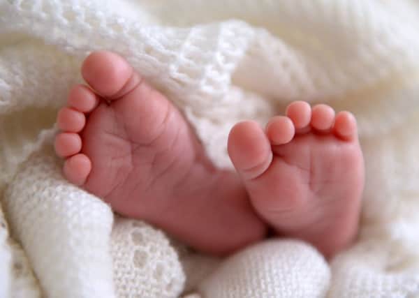 A new born baby's feet are visible peeking out of a shawl