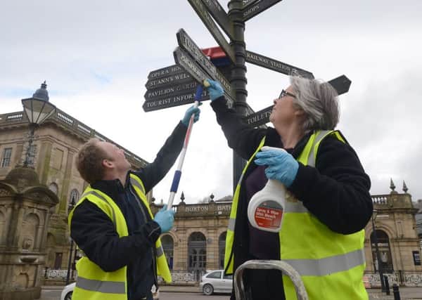 John and Tina Heathcote cleaning a signpost in The Crescent.