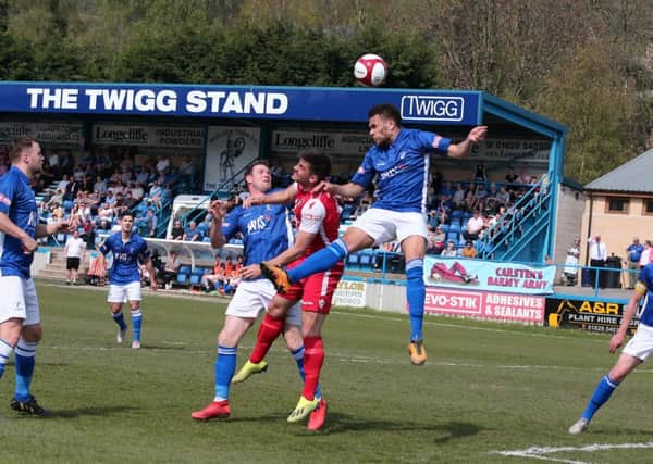 Matlock's Dwayne Wiley rises to head clear another Buxton attack.