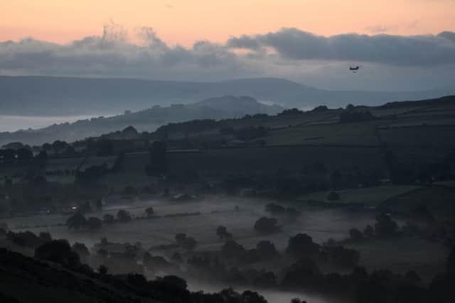 Mist is seen in the valleys before sunrise as a Chinook helicopter prepares to drop sandbags onto the dam wall at Toddbrook reservoir following a severe structural failure after heavy rain (Photo by Leon Neal/Getty Images)