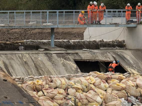 Assessing the damage at Toddbrook Reservoir. Photo - OLI SCARFF/AFP/Getty Images