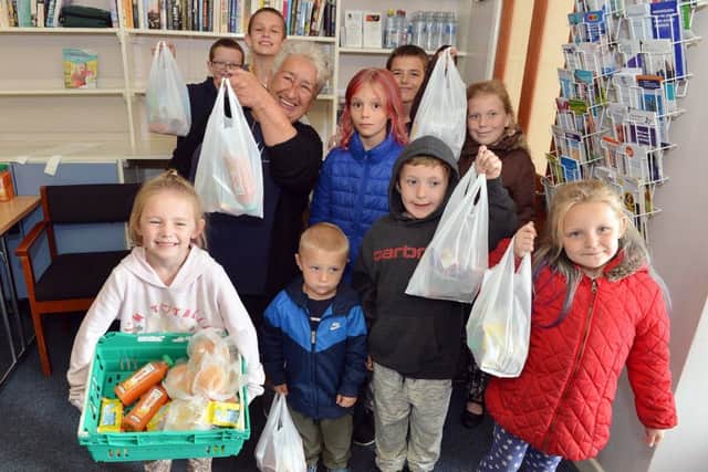 Lia with local youngsters and the packed lunches which have been provided at the summer camp.