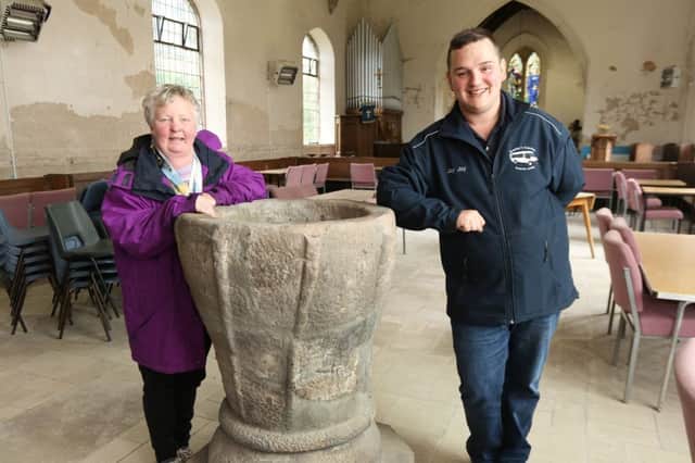 Angela Campeau and Jason Bentley with the ancient Saxon Font that survived the bombing and attracts interest from many visitors