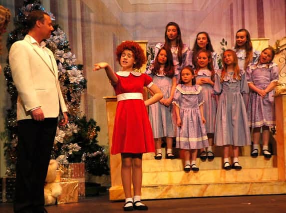 Niamh Mulvihill as Annie, pictured with the orphans and Matt Darsley as Daddy Warbucks.