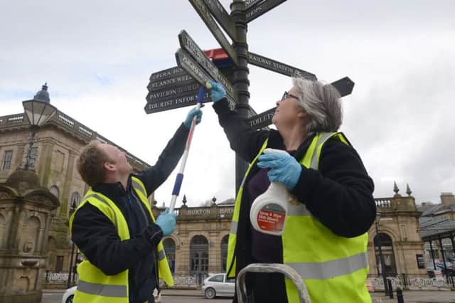 Buxton Town Team's big spring clean, John and Tina Heathcote cleaning a signpost in The Crescent