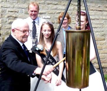 Albert Knowles and Hayfield May Queen Ruth Eastwood strike the gong to signal the opening of the exhibition, watched by Peter Eastwood, Chairman of Hayfield Parish Council, vicar Hilary Edgerton and Junior May Queen Hannah. Photo contributed.