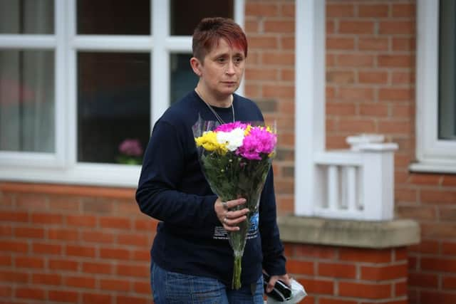 A resident takes flowers to the scene of the fire.