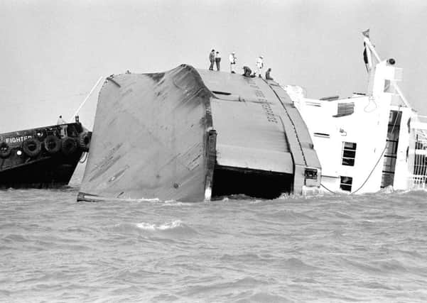 Rescue workers stand on the side of the half-submerged car ferry Herald of Free Enterprise which capsized off the Belgian port of Zeebrugge.