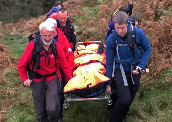 Buxton and Edale team members carrying the casualty towards the waiting ambulance.