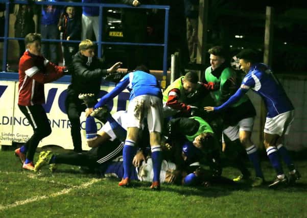 Jubilent players pile on top of scorer Adam Yates after he scored Matlock's third goal.