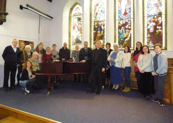 Church members with the newly-restored grand piano at Buxton URC.